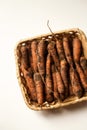 Fresh unwashed carrots in a square basket