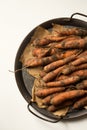 Unwashed carrots in a metal tray on a white