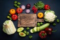 Fresh various vegetables, cut zucchini, wooden cutting board and knife on rustic dark background top view. Cooking