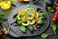 Fresh vegan avocado salad with oranges and spinach on a black plate. Rustic style. Top view. Royalty Free Stock Photo