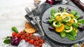Fresh vegan avocado salad with oranges and spinach on a black plate. Rustic style. Top view. Royalty Free Stock Photo