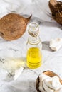 Fresh vegetable coconut oil in a bottle and pieces of coconut on the table. Vertical and above view