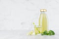 Fresh vegetable green spinach and celery juice in glass bottle mock up with glass, straw, stems, leaves in soft light. Royalty Free Stock Photo