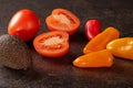 Fresh vegetable mix of tomatoes, bell peppers, and avocado on black table