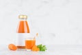 Fresh vegetable orange carrot juice in glass bottle with blank label mock up with glass, straw, green parsley, slices in soft.