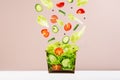 Fresh vegetable salad in craft box for take away food with falling slices of ingredients - cherry tomato, cucumber, green salad. Royalty Free Stock Photo