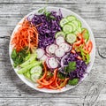 Fresh vegetable salad with red cabbage, cucumber, radish, carrots, sweet peppers, red onion and parsley on a white plate. Royalty Free Stock Photo