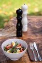 Fresh vegetable salad served on a bowl with mixed green leaves, eggs, black olives and tomato on a wooden rustic table with Royalty Free Stock Photo