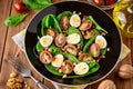 Fresh vegetable salad with spinach, cherry tomatoes, quail eggs, pomegranate seeds and walnuts in black plate on wooden table. Royalty Free Stock Photo