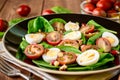 Fresh vegetable salad with spinach, cherry tomatoes, quail eggs, pomegranate seeds and walnuts in black plate on wooden table. Royalty Free Stock Photo