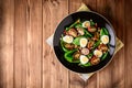 Fresh vegetable salad with spinach, cherry tomatoes, quail eggs, pomegranate seeds and walnuts in black plate on wooden table. Royalty Free Stock Photo