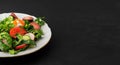 Fresh vegetable salad with tomatoes, radish eggs, caviar and onions. Black background with copy space. Close-up