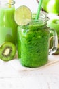 Fresh vegetable smoothie in jar mug, green fruit juice in bottle, kiwi, citrus, apples outdoors, sunlight spots Royalty Free Stock Photo