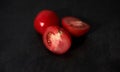 Fresh vegetables on black kitchen table. Minimalistic restaurant menu. Two clean red tomatoes with water drops on black background Royalty Free Stock Photo