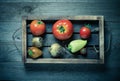 Fresh vegetables in a burned rustic texture box for background. Rough weathered wooden board. Toned Royalty Free Stock Photo