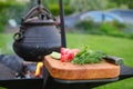 Fresh vegetables on cutting board and cast iron pot over the fire on background Royalty Free Stock Photo