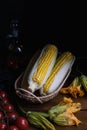 Fresh vegetables dark still life, tomatoes, corn zucchini flowers, basil, olive oil