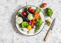 Fresh vegetables - eggplant, radish, bell pepper, tomatoes, thyme, oregano in an enamel bowl on a light background.