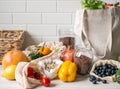 Fresh vegetables and fruits in eco cotton bags and cereals in glass jars on table in the kitchen