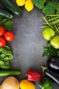 Fresh vegetables, fruits, herbs on dark stone table Frame of fresh veggies. Mockup for menu or recipe. Spring vitamins