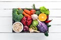 Fresh vegetables and fruits in a wooden box on a white wooden background. Organic food.