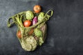 Fresh vegetables in a green string bag on a black background. Cauliflower, tomatoes, artichokes, asparagus and zucchini Royalty Free Stock Photo