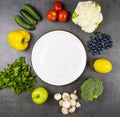 Fresh vegetables and herbs around a round empty plate on a table top view. The concept of healthy eating. Royalty Free Stock Photo