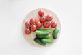 Fresh vegetables lie on a white background wooden cutting board, top view. Tomatoes on a branch, cucumbers gherkins. Royalty Free Stock Photo