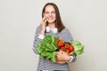 Fresh vegetables from the market. Healthy vegetarian lifestyle. Cheerful joyful brown haired woman talking mobile phone buying