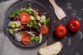 Fresh vegetables salad with purple cabbage, white cabbage, lettuce, carrot in dark clay bowl on black background. Top view Royalty Free Stock Photo