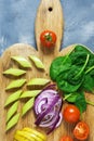 Fresh vegetables are sliced on a cutting board, cherry tomatoes, spinach, cabbage, celery. Vegetarian dinner. Top view. Royalty Free Stock Photo