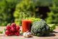 Fresh vegetables and tomato juice on old wooden table, over green nature background Royalty Free Stock Photo