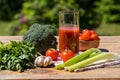 Fresh vegetables and tomato juice on old wooden table, over green nature background Royalty Free Stock Photo