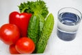 Fresh vegetables tomatoes, bell peppers, cucumbers and lettuce are in a plastic container next to a glass of water on the Royalty Free Stock Photo