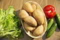 Fresh vegetables. Tomatoes, cucumbers and lettuce on a wooden table. Potatoes in a wicker basket. Royalty Free Stock Photo