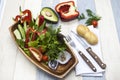 Fresh vegetables on a wooden plate with fork and knife. Red pepper, tomato, cucumber, radish, parsley, dill healthy diet. Royalty Free Stock Photo