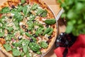 Fresh vegetarian pizza with spinach, black olives and almonds on wooden table in restaurant. Royalty Free Stock Photo