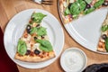 Fresh vegetarian pizza with spinach, black olives and almonds on wooden table in restaurant. Royalty Free Stock Photo