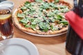 Fresh vegetarian pizza with spinach, black olives and almonds on wooden table in restaurant. Royalty Free Stock Photo