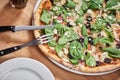 Fresh vegetarian pizza with spinach, black olives and almonds on wooden table in restaurant. Royalty Free Stock Photo