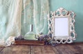 Fresh vintage perfume bottle next to aromatic flowers and antique blank frame on wooden table. retro filtered image