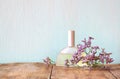 Fresh vintage perfume bottle next to aromatic flowers on wooden table. retro filtered image