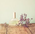 Fresh vintage perfume bottle next to aromatic flowers on wooden table. retro filtered image Royalty Free Stock Photo