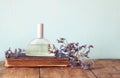 Fresh vintage perfume bottle next to aromatic flowers on wooden table. retro filtered image Royalty Free Stock Photo