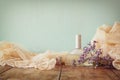 Fresh vintage perfume bottle next to aromatic flowers on wooden table. retro filtered image