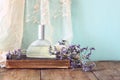 Fresh vintage perfume bottle next to aromatic flowers on wooden table. retro filtered image