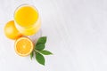 Fresh vitamin summer yellow beverage of ripe oranges with green leaf on light white wood background, top view, border. Royalty Free Stock Photo