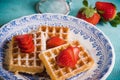 Fresh waffles with strawberries and strainer on table Royalty Free Stock Photo