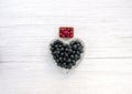 Fresh washed black currants berries in a heart shaped bowl on gray with copy space. Red currant berries in small basket. Close up Royalty Free Stock Photo