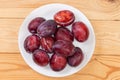 Fresh washed plums on dish on rustic table, top view Royalty Free Stock Photo